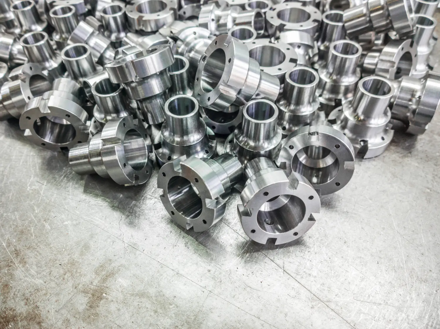 Glänzende Stahlteile nach dem CNC-Drehen, Bohren und Bearbeiten der Stahloberfläche mit selektivem Fokus.