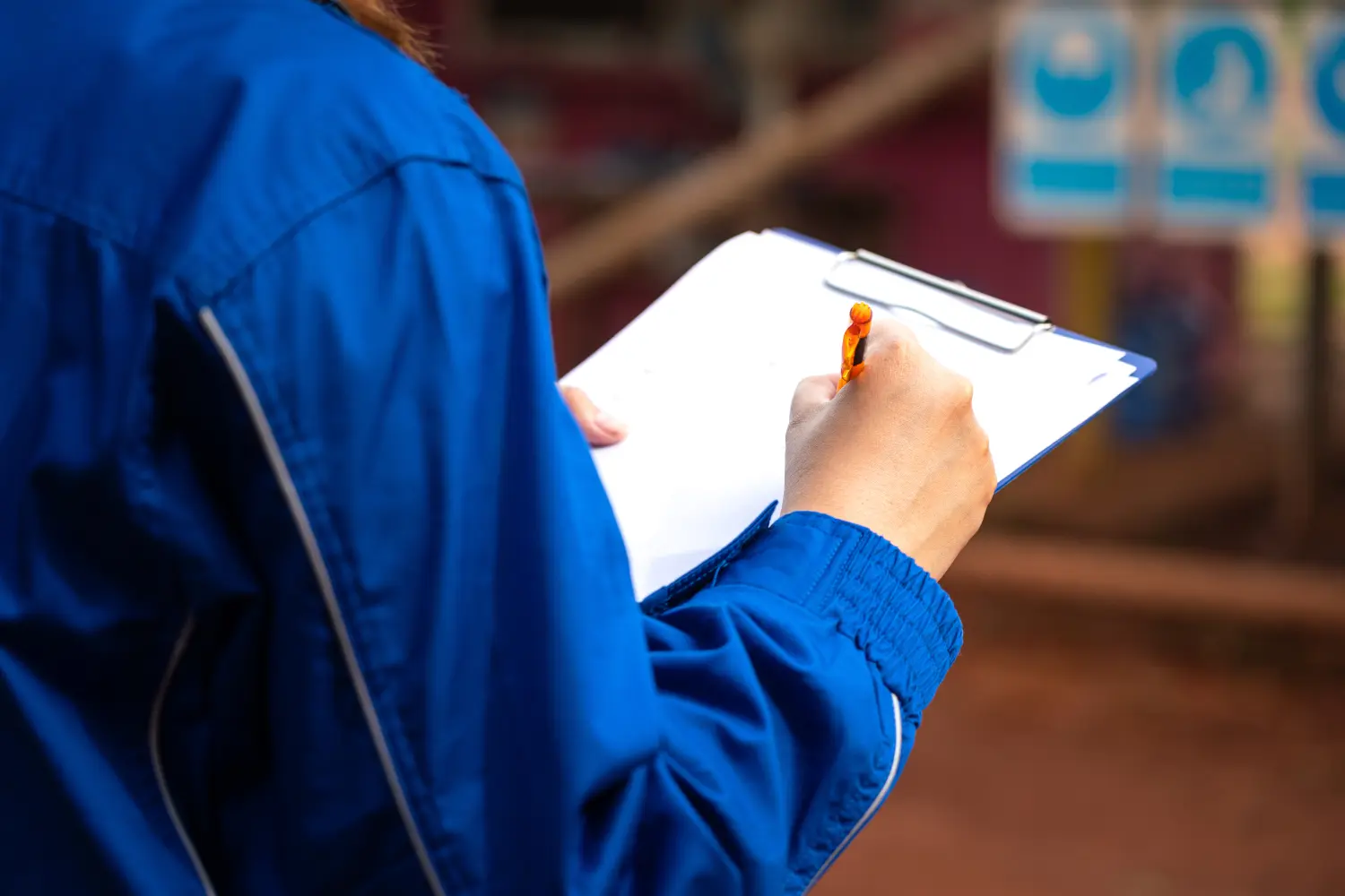Ein Sicherheitsbeauftragter oder Manager schreibt auf Papier, um sich während des Sicherheitsaudits auf der Baustelle Notizen zu machen. Industrielle Sicherheit arbeiten Aktion Szene, Nahaufnahme und selektiven Fokus.